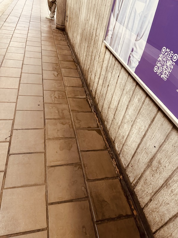 Long stretch of stained tile flooring running alongside weathered board-formed concrete construction barriers in a MARTA station concourse.