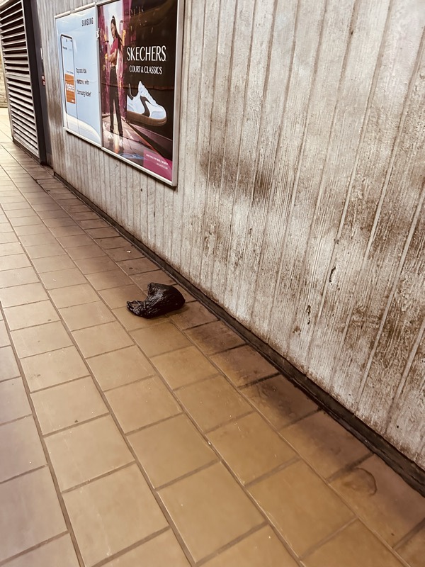 Discarded item left on station floor next to advertising panels and weathered wall paneling.