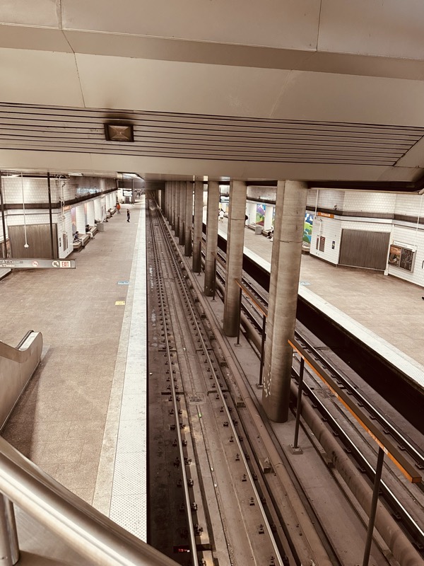 An overhead view down a long MARTA station showing two parallel platforms flanking the tracks.