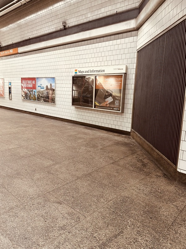 A station concourse near a Maps and Information board with discolored granite-look floor tiles.