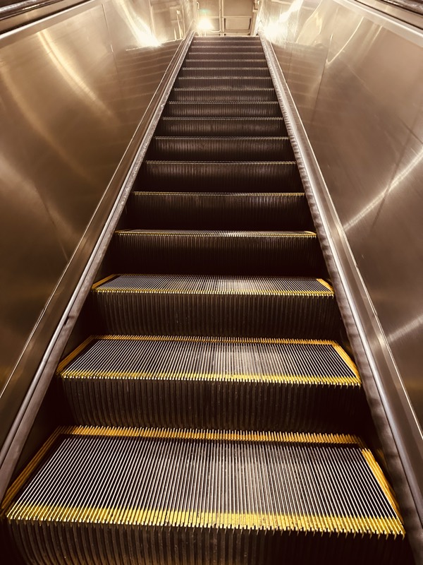 A well-lit MARTA escalator going up, with clean treads and stainless-steel side walls.
